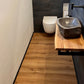 Klick-Vinylboden in Braun in Gäste-WC mit schwarzen Wandfliesen und Steinwaschbecken in Schwarz