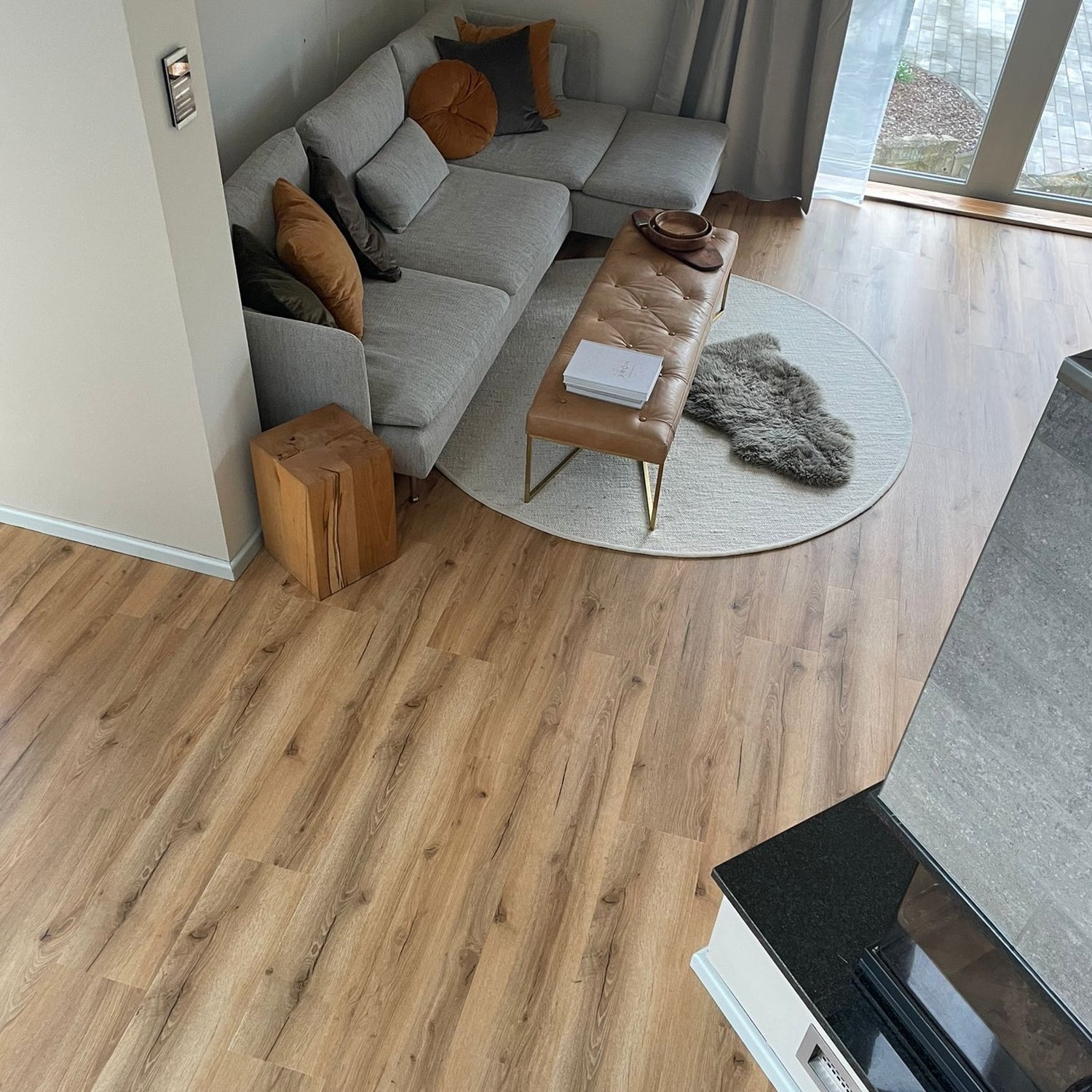 Vogelperspektive Klick-Vinylboden in Braun in modernem Wohnzimmer mit grauer Couch, Teppich und Kamin