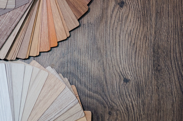Einige Musterkarten für die Kunden um sich die richtige Farbe auszusuchen auf einem dunkelbraunen Holztisch.